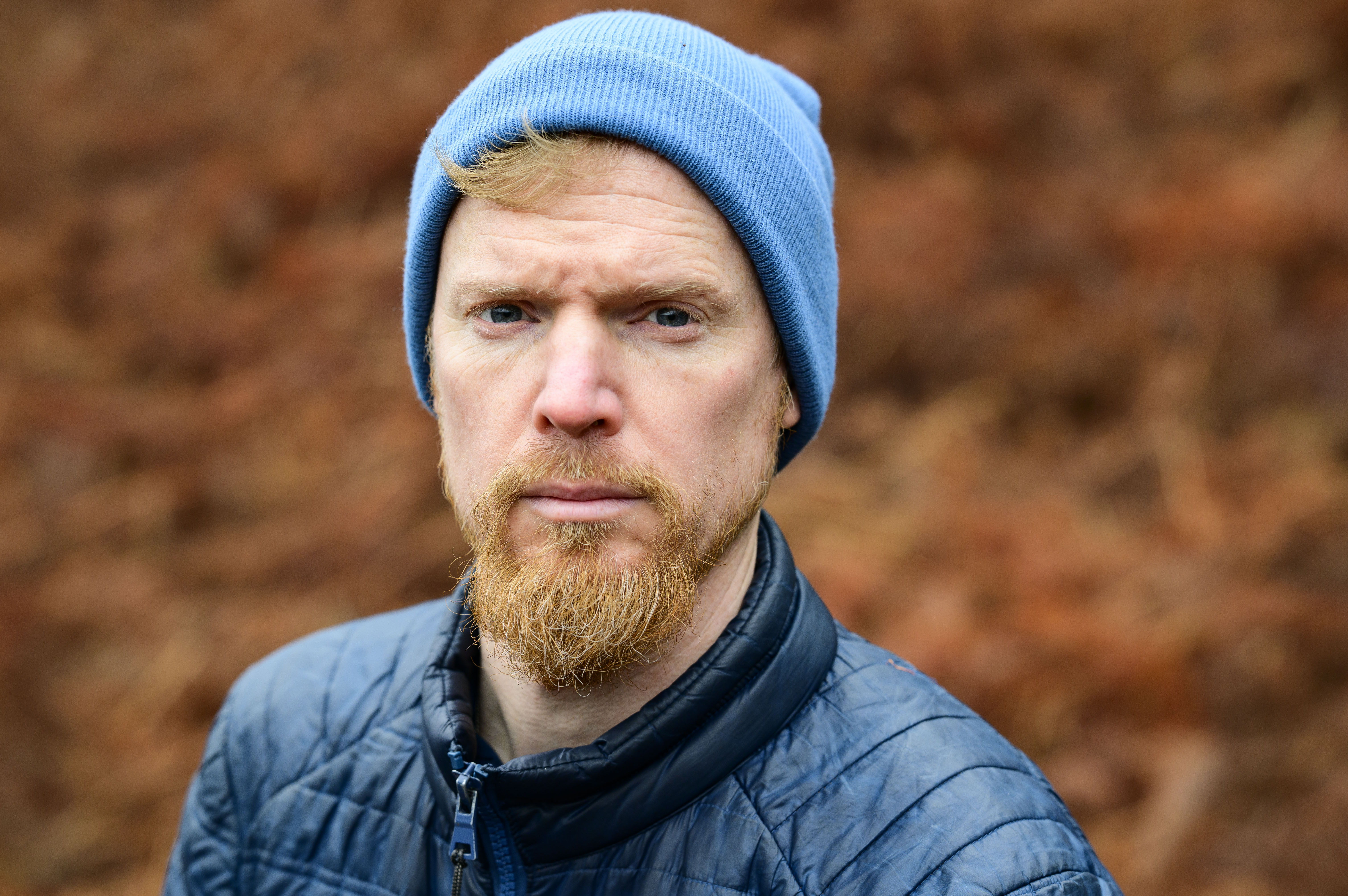 Viltrox AF 85mm F1.4 Pro lens sample gallery: man in a blue beanie, with blurry bronze-colored ferns in the background