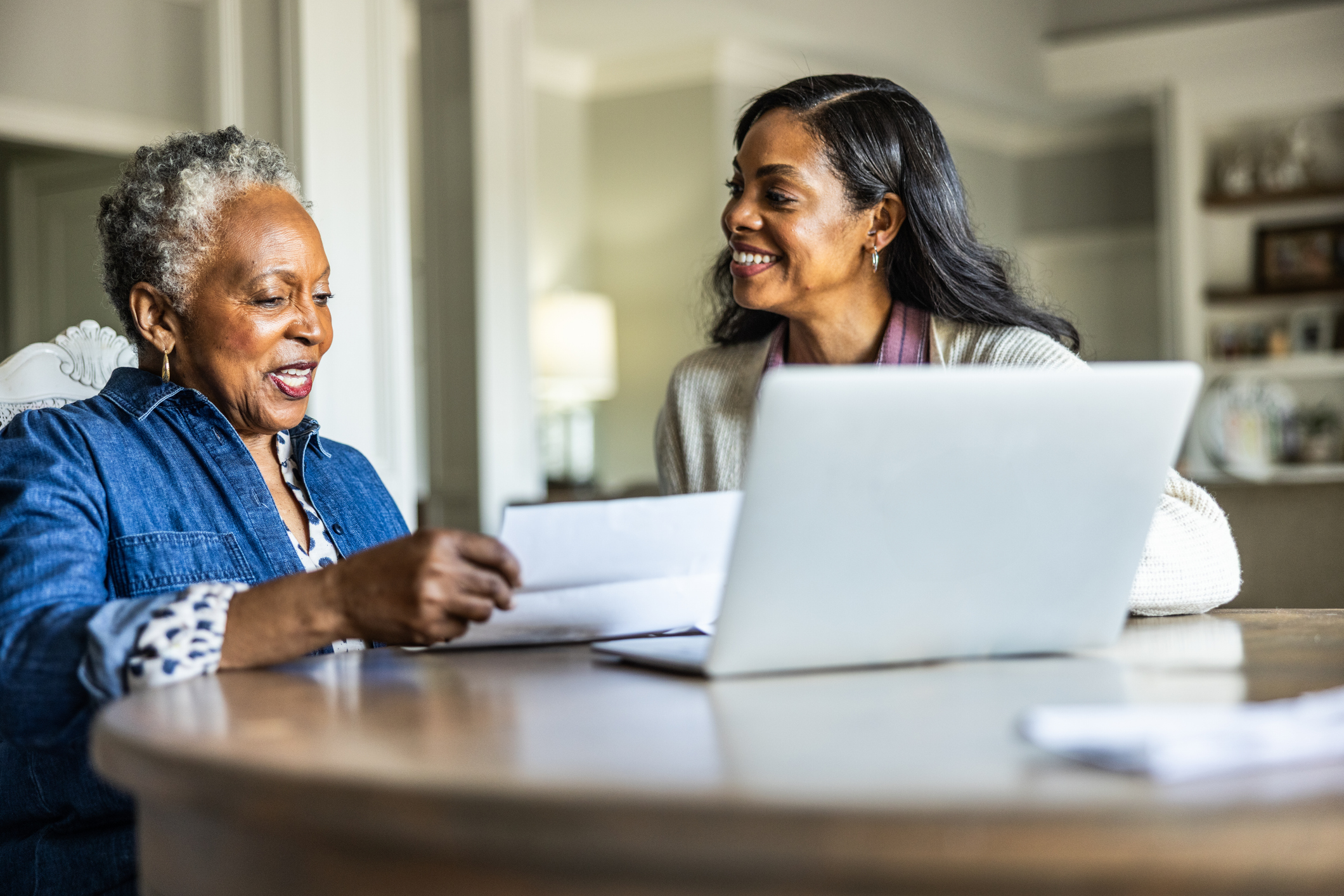 A woman and her daughter organising her pension paper work on a laptop