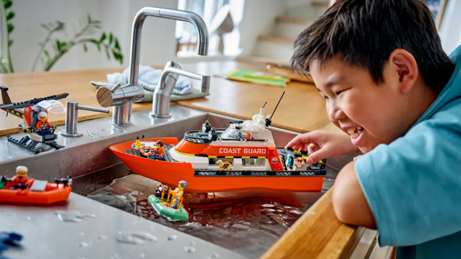 A child plays with the Lego Coast Guard Rescue Boat set in the kitchen sink