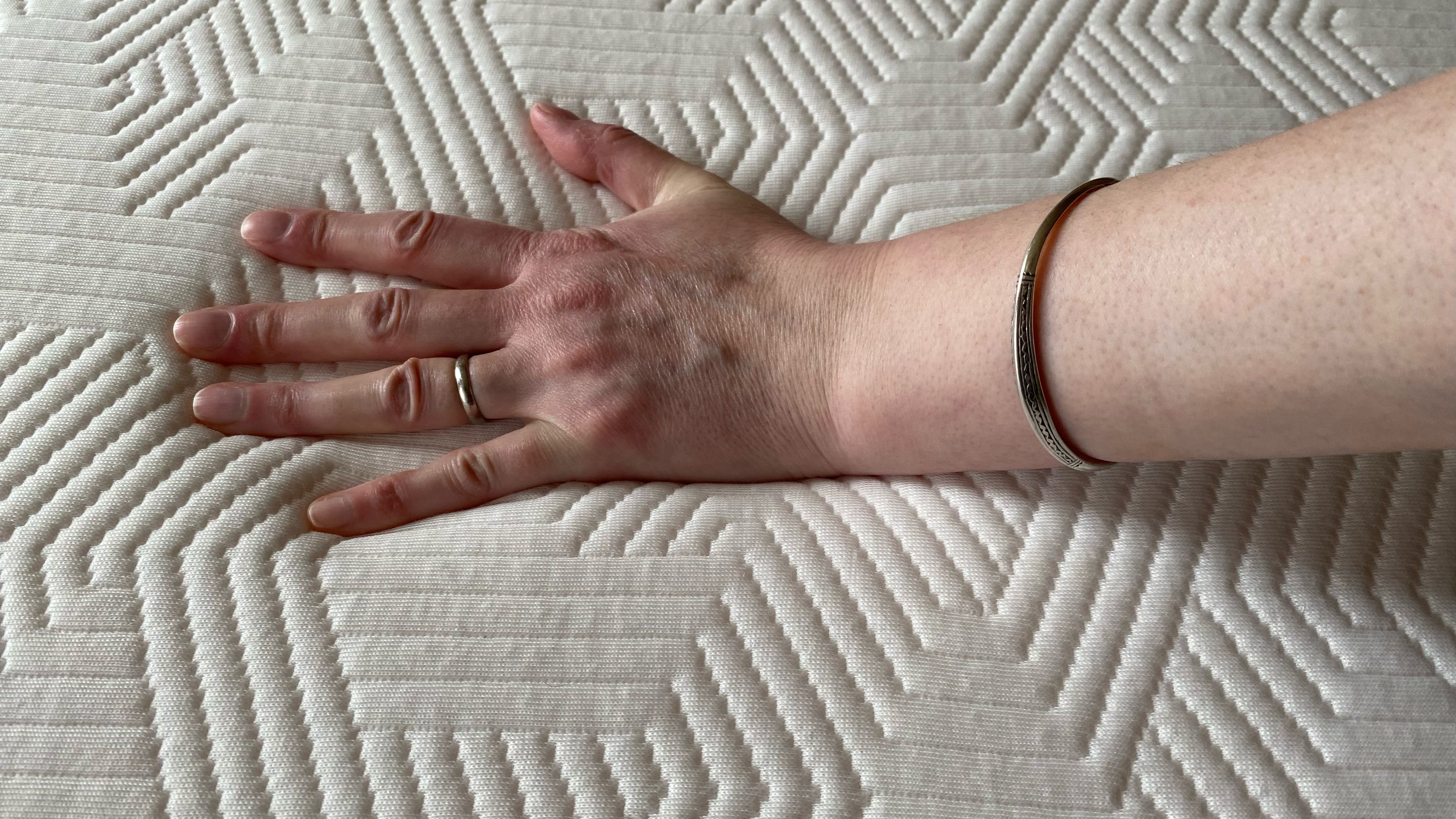Our lead reviewer places her hand on the Brook + Wilde Suprema Mattress to see how cool it feels after sleeping on it