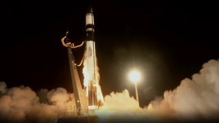 a black and white rocket launches from a pad at night