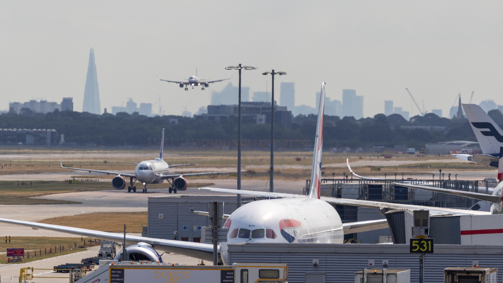 A plane coming in to land at Heathrow, with London skyscrapers in the background