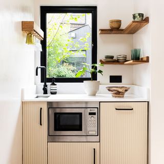 small kitchen in garden studio with open shelving and microwave