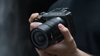 Hasselblad XCD 20-35E lens, mounted to a Hasselblad X2D, being handheld in front of a waterfall