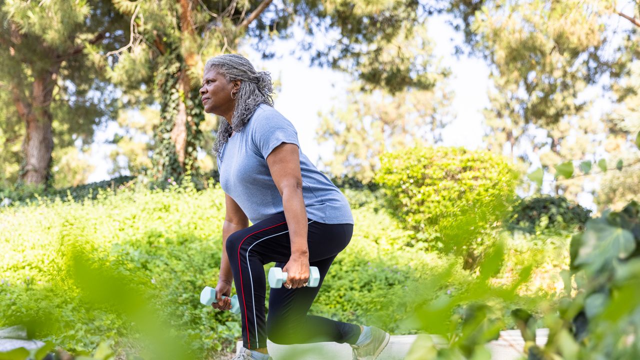 A woman performing a lunge with dumbbells