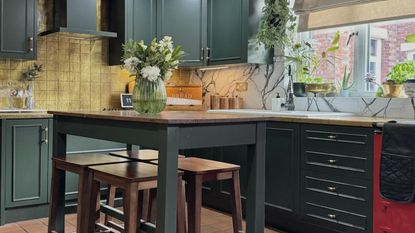 green kitchen with gold leaf splash back and kitchen table with bar stools