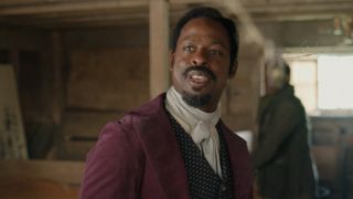 Sterling K. Brown smiling in a purple suit jacket and white shirt