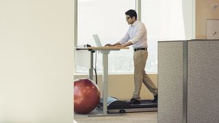 Under desk treadmill deals: Man walking on under desk treadmill in an office