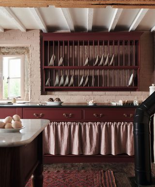 Red cabinets and plate rack, white stone walls