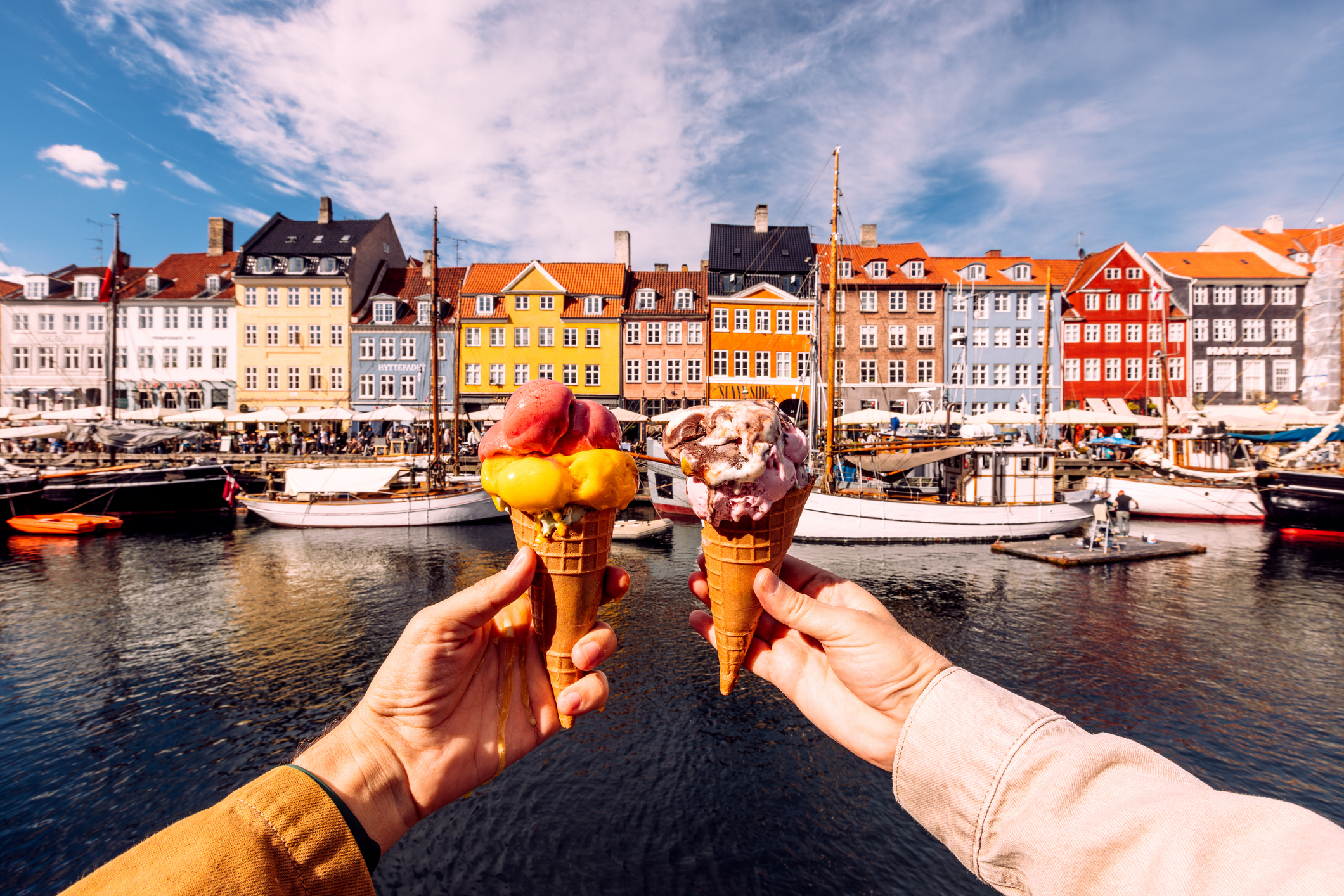 Two persons holding colourful ice cream by Nyhavn harbour in Copenhagen, Denmark