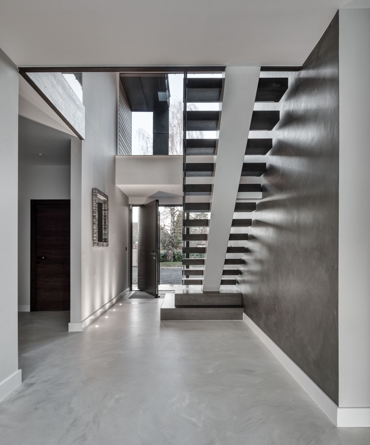 double height hallway with grey floating staircase, grey marble walls and floor