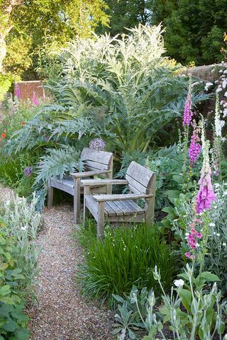 a pretty seating area flanked by pink and white foxgloves
