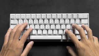 An image of someone typing on a white wireless mechanical keyboard