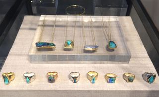four necklaces and eight rings, all with different shaped opals, set out on a display cabinet