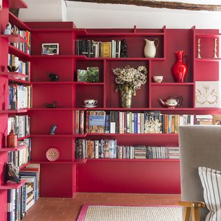 room with red open books shelve floor rug and red vase