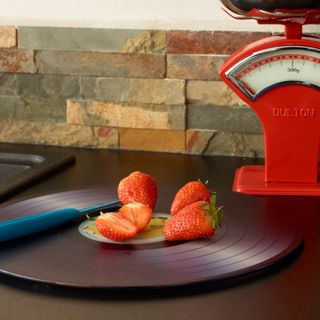 Strawberries on a cutting board next to red kitchen scales