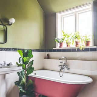 A green-painted bathroom with a pink bathtub