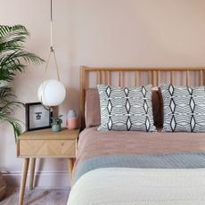 bedroom with blush pink walls and matching bed next to bedside table