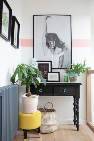 Debbie Goodwin: landing nook with console table, black and white photograph of woman, white walls with pink horizontal stripe paint effect