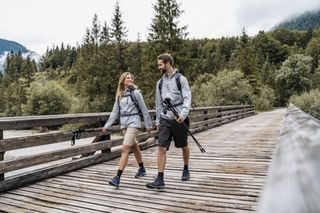 A happy couple enjoying a hike walking over a wooden bridge.