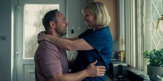 stephan graham and Christine Tremarco as eddie miller and Manda Miller hugging each other in the kitchen in a still from the tv show adolescence