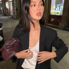 Fashion influencer @mimixn in NYC wearing a chic black blazer with the viral COS burgundy leather pouch handbag.