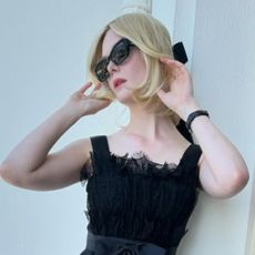 Elle Fanning on her balcony at the Cannes Film Festival wearing a black dress with a coordinating black bow