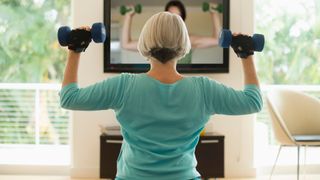 A woman works out with weights to a TV fitness workout