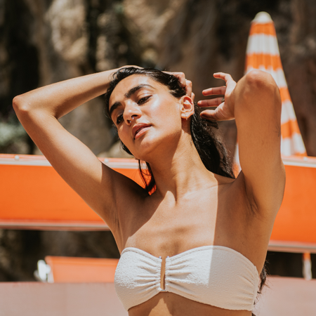 Woman on the beach in the sun touching her hair