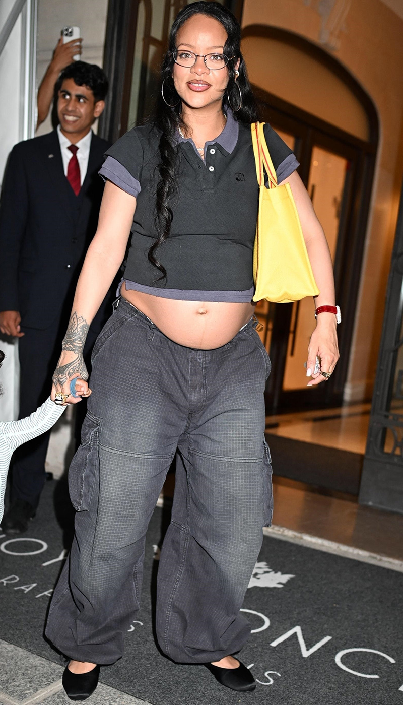 Rihanna wearing a polo shirt, grey baggy pants, and a yellow tote bag