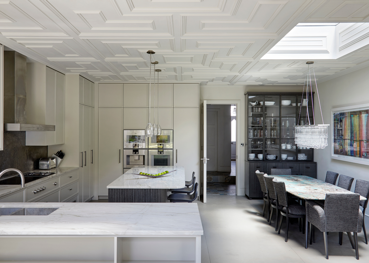an open plan kitchen space with hanging pendant lights a seating area and decorative ceiling paneling