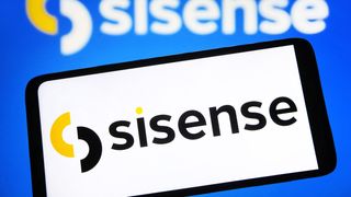 The Sisense logo on a phone, held in front of a blurred Sisense logo shown on a larger screen.