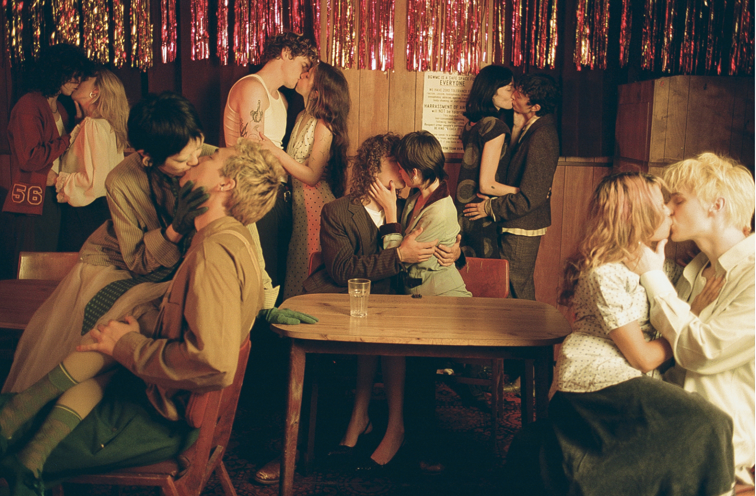 A lively gathering with multiple couples engaged in intimate moments, set against a backdrop of colorful streamers and a cozy atmosphere