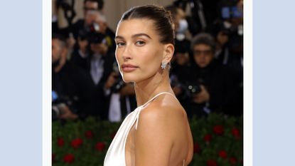 Hailey Bieber wears a white silk dress as she attends the 2022 Met Gala, for a piece on 'Hailey Bieber White Dress'/ in a blue template