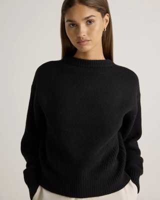 a model wears a crewneck sweater from quince in front of a plain backdrop