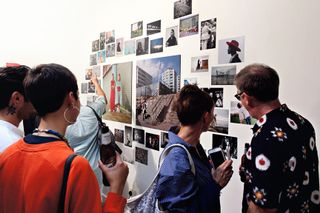 A gallery of people looking at art on a wall