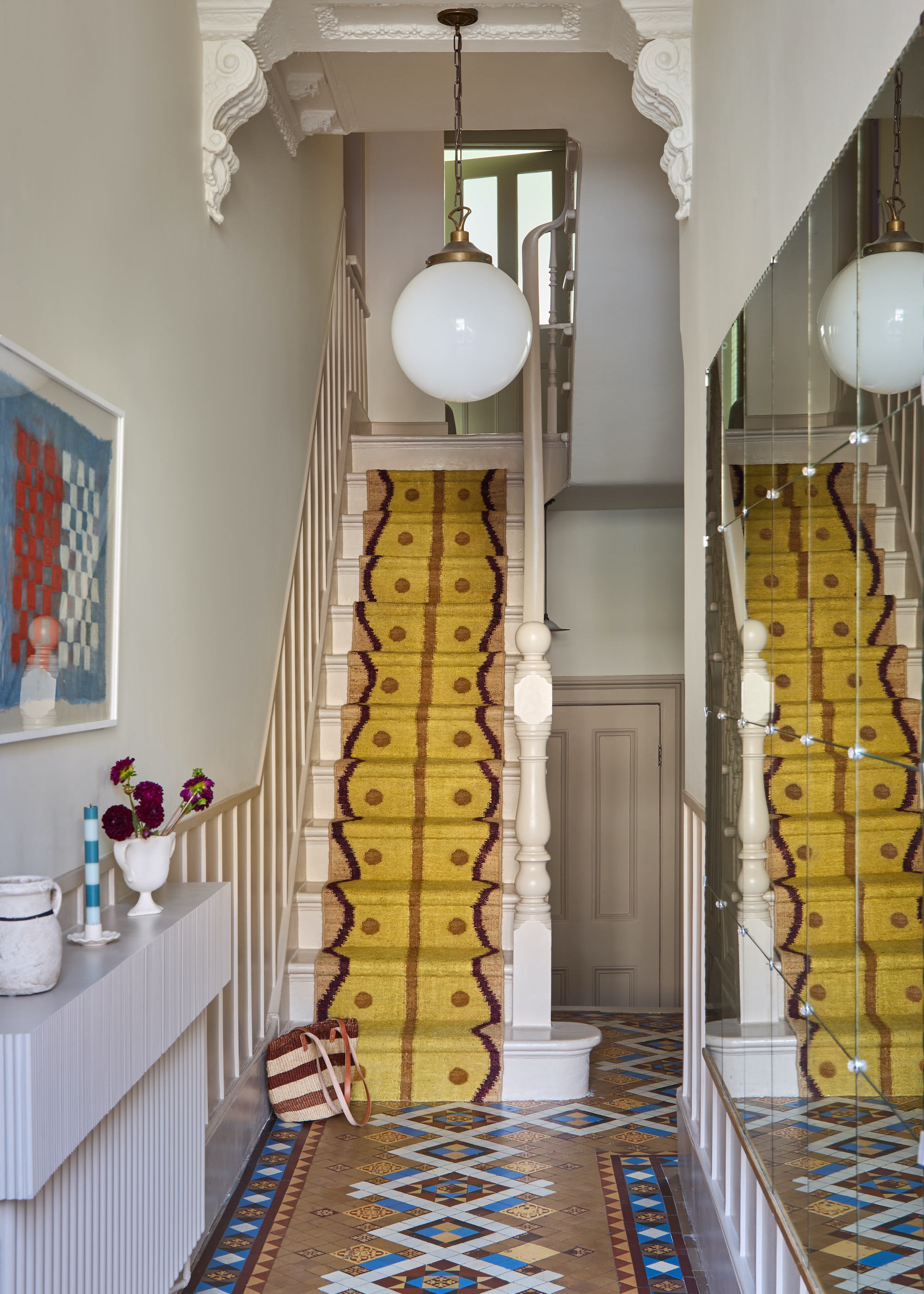 staircase with bright yellow runner and victorian tiled hallway floor