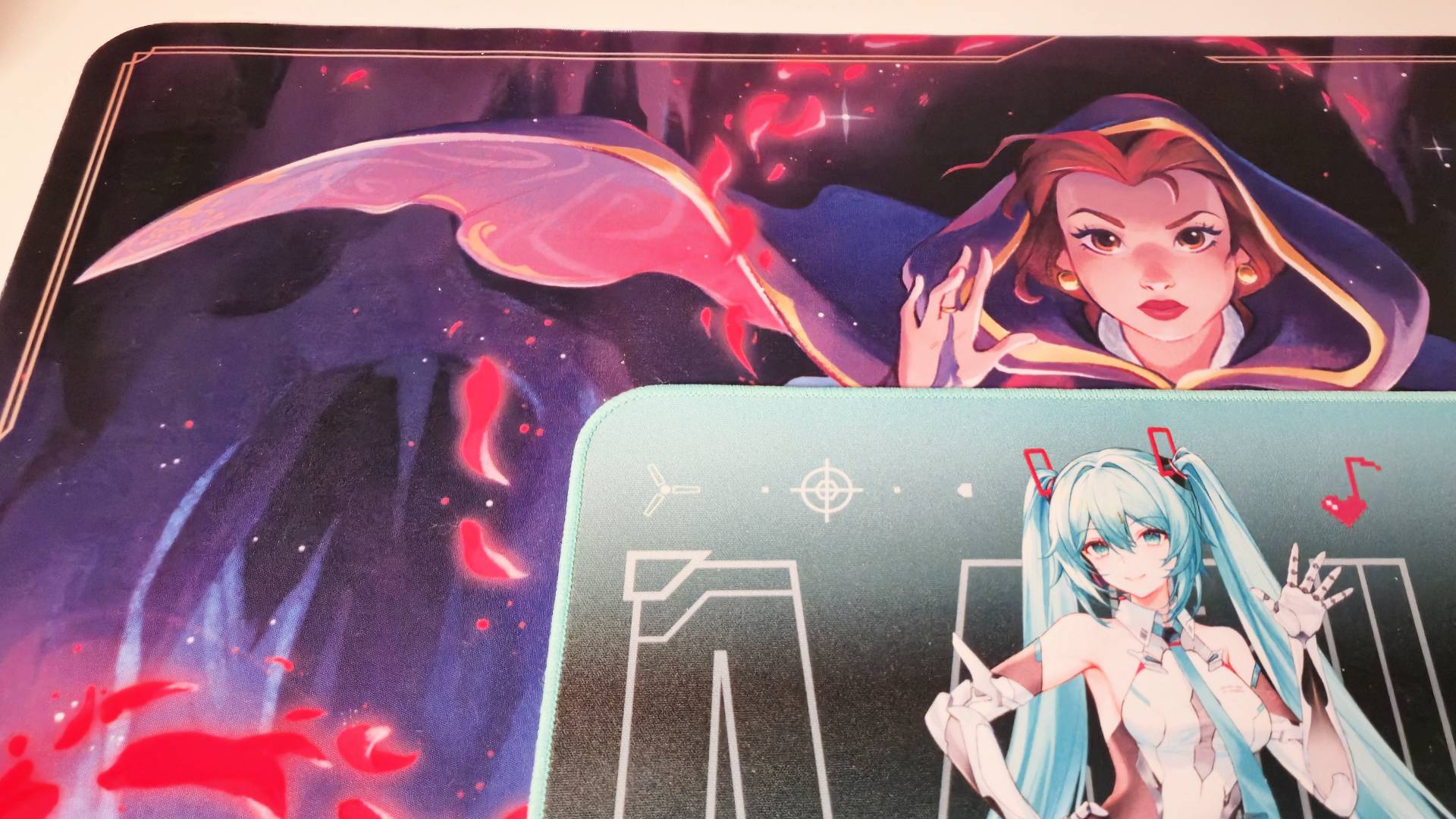 Photo of the Asus TUF Gaming Hatsune Miku mouse mat sitting on a Lorcana playmat.
