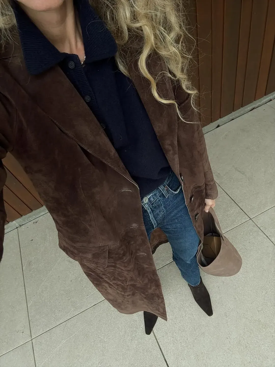 A woman wears pointy toe suede boots with jeans