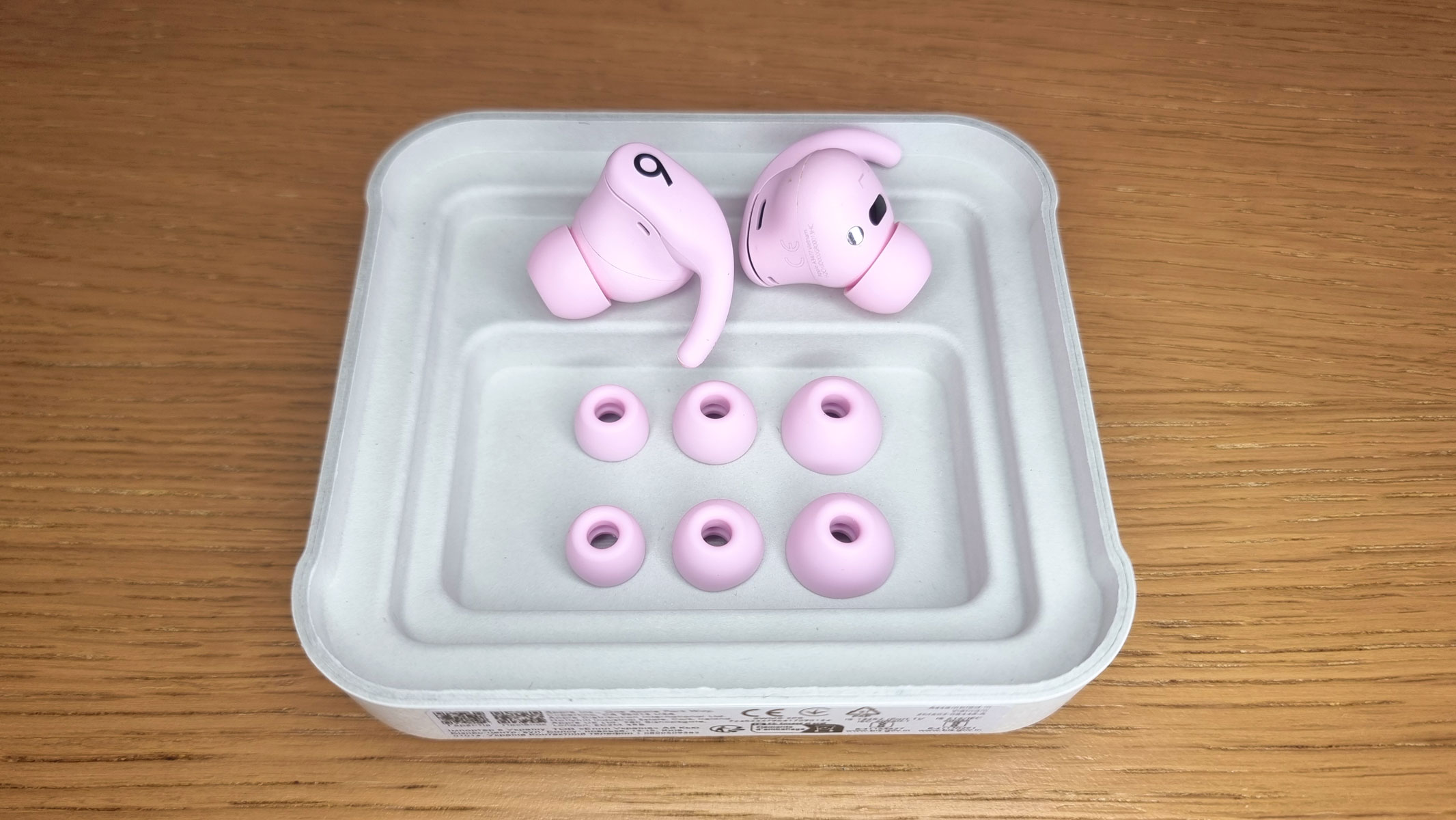 A picture of the Beats Powerbeats Fit earbuds with spare eartips 