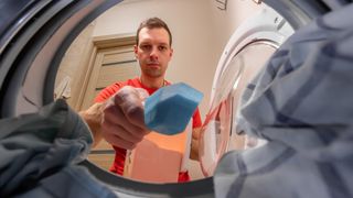 Man putting detergent in drum of front-loading washing machine