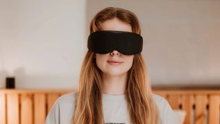 A woman wearing a black Aura Smart Sleep Mask