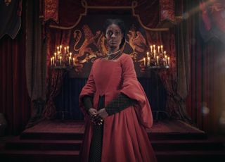 Jodie Turner-Smith as Anne Boleyn, wearing a red dress and standing in the throne room