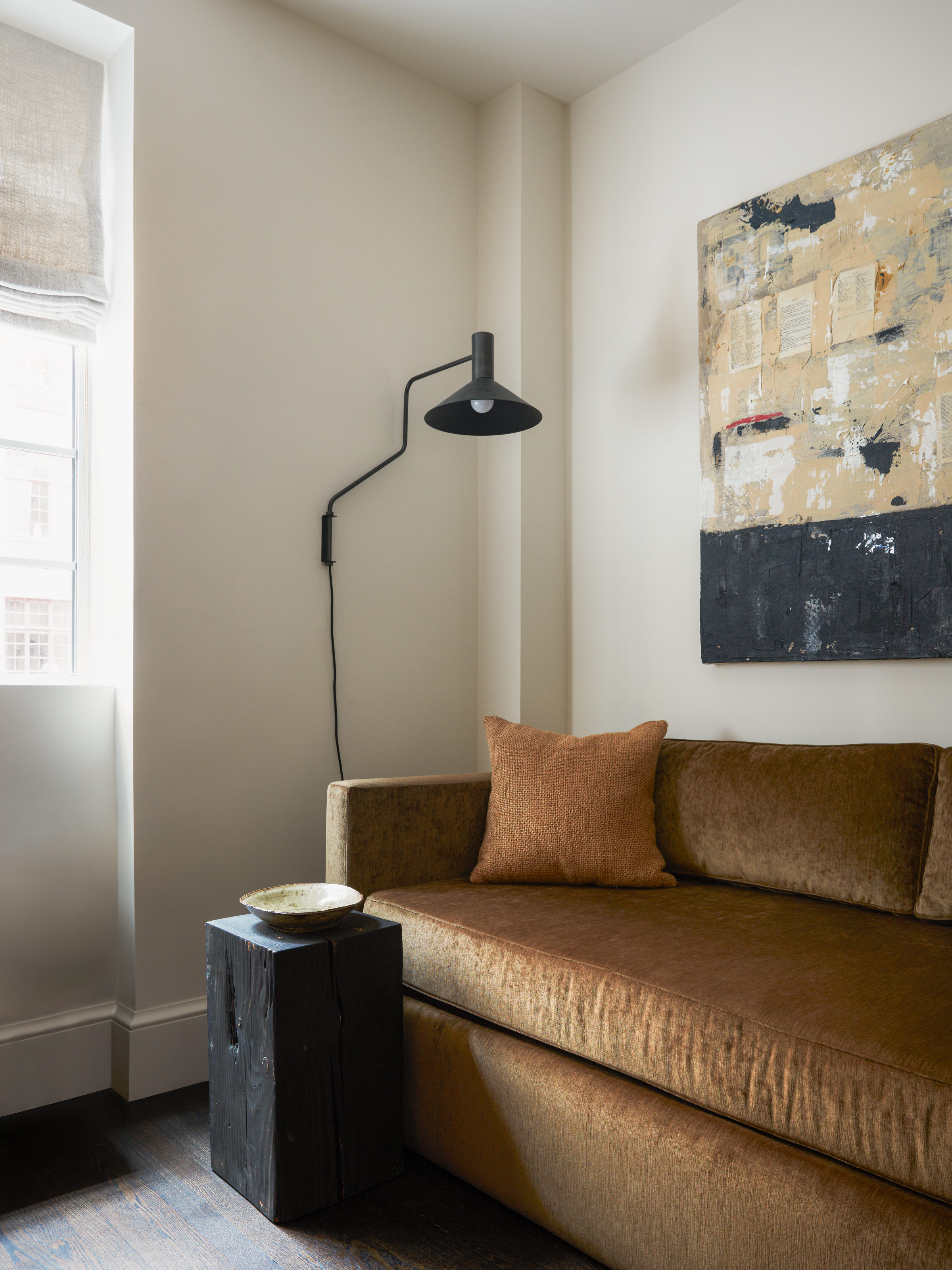 Seating area with ochre velvet sofa and black wood side table
