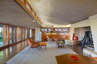 A living room with banquette seating, mid-Century furniture and leather chairs