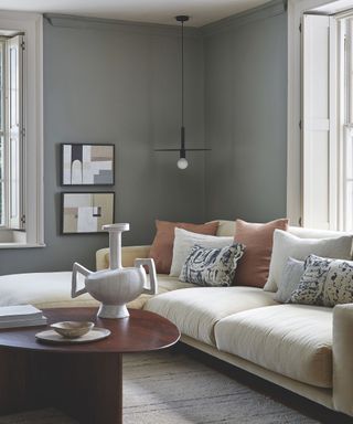 living area with greyish green walls and big cream sofa and coffee table with sculpture