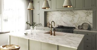 quiet luxury kitchen with soft sage green cabinets, marble countertops and splashback with brass taps