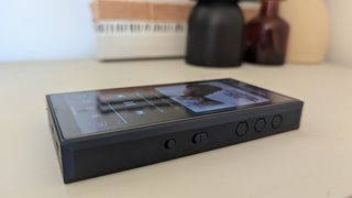 Fiio M23 portable music player lying flat on white shelf, detail of controls