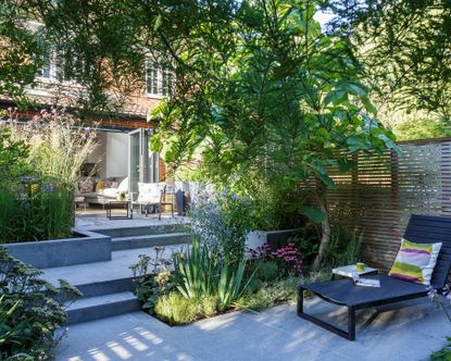 How to plan a small garden featuring gray steps, wooden screens, a black sunlounger and a mix of planting.