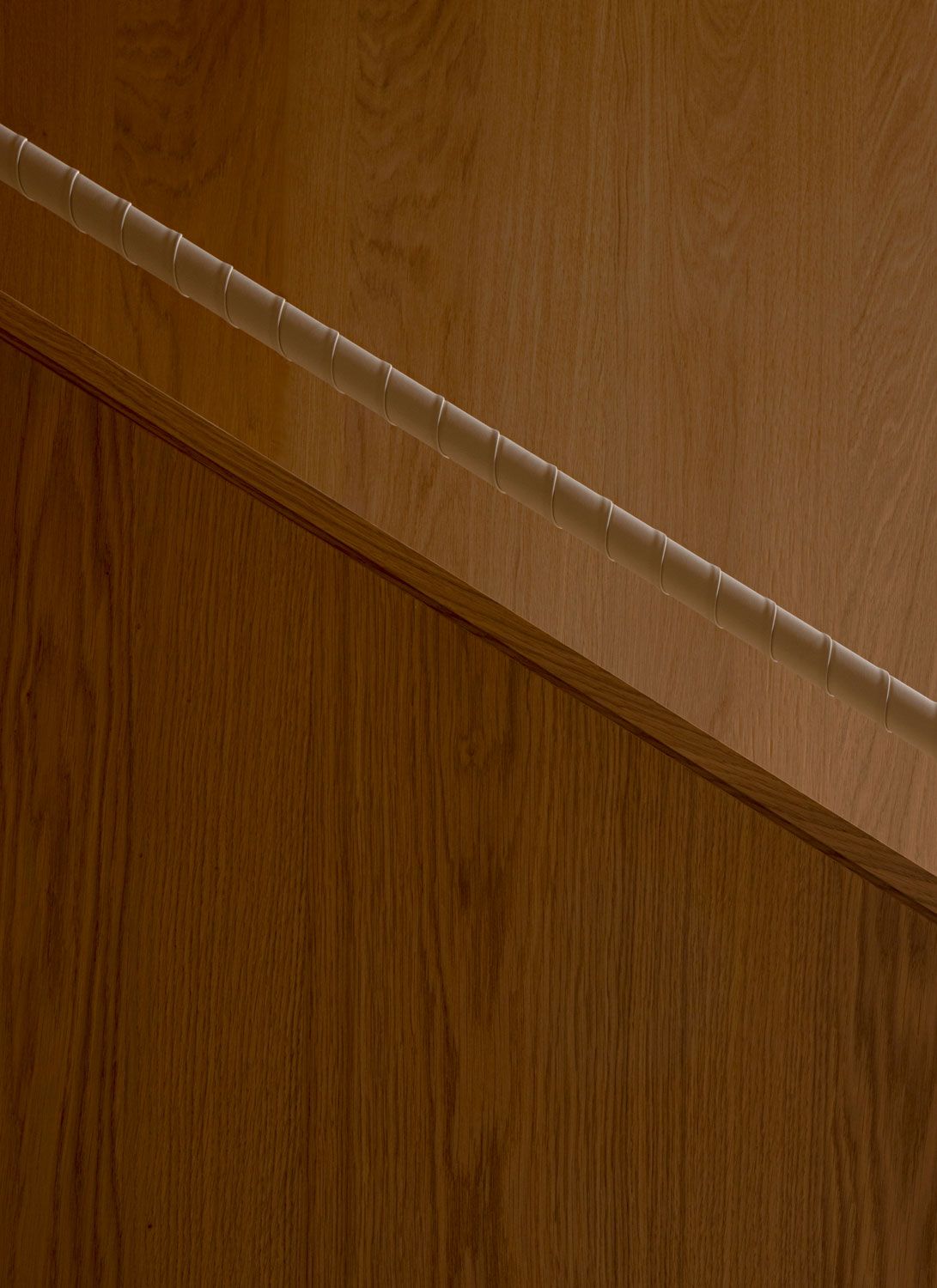 Close-up of the leather-wrapped staircase handrail against oak panelling at 262 Fifth Avenue by Norm Architects